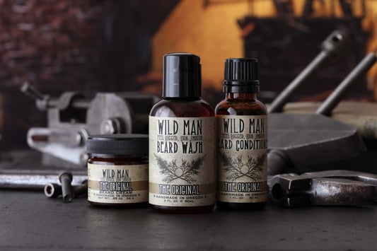 3 beard care products with dark workshop background surrounded by tools