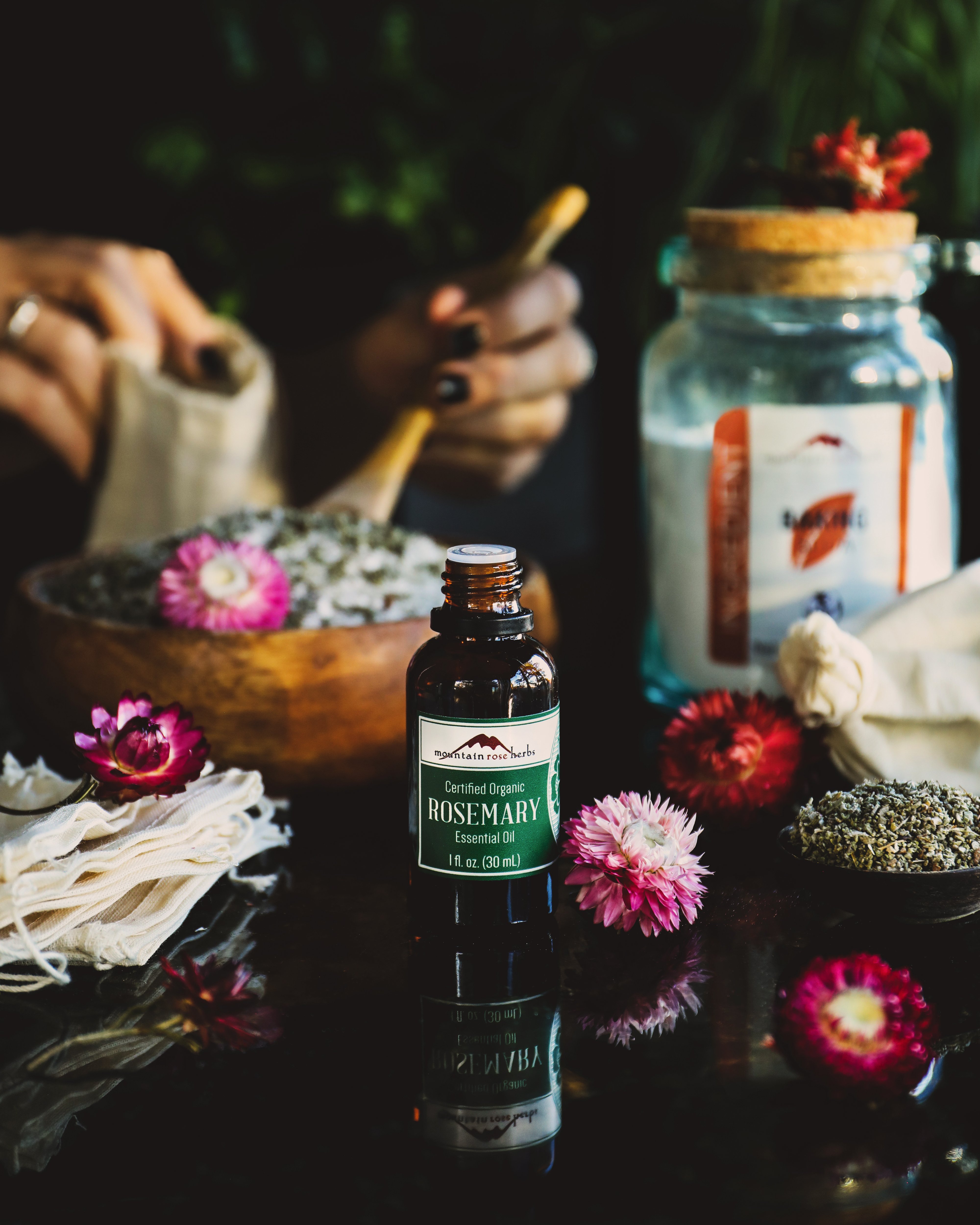 Rosemary essential oil and herbs set out to make a baking soda, sage, & rosemary boot and shoe deodorizer