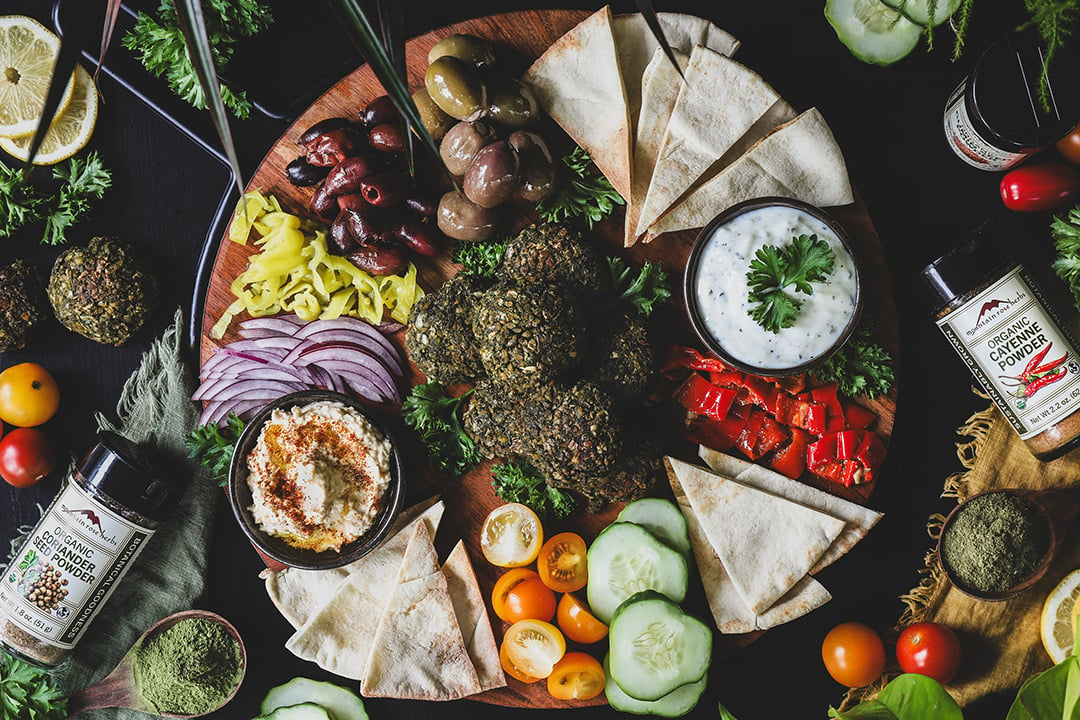 Colorful falafel platter with pita, veggies, olives, and dips. 